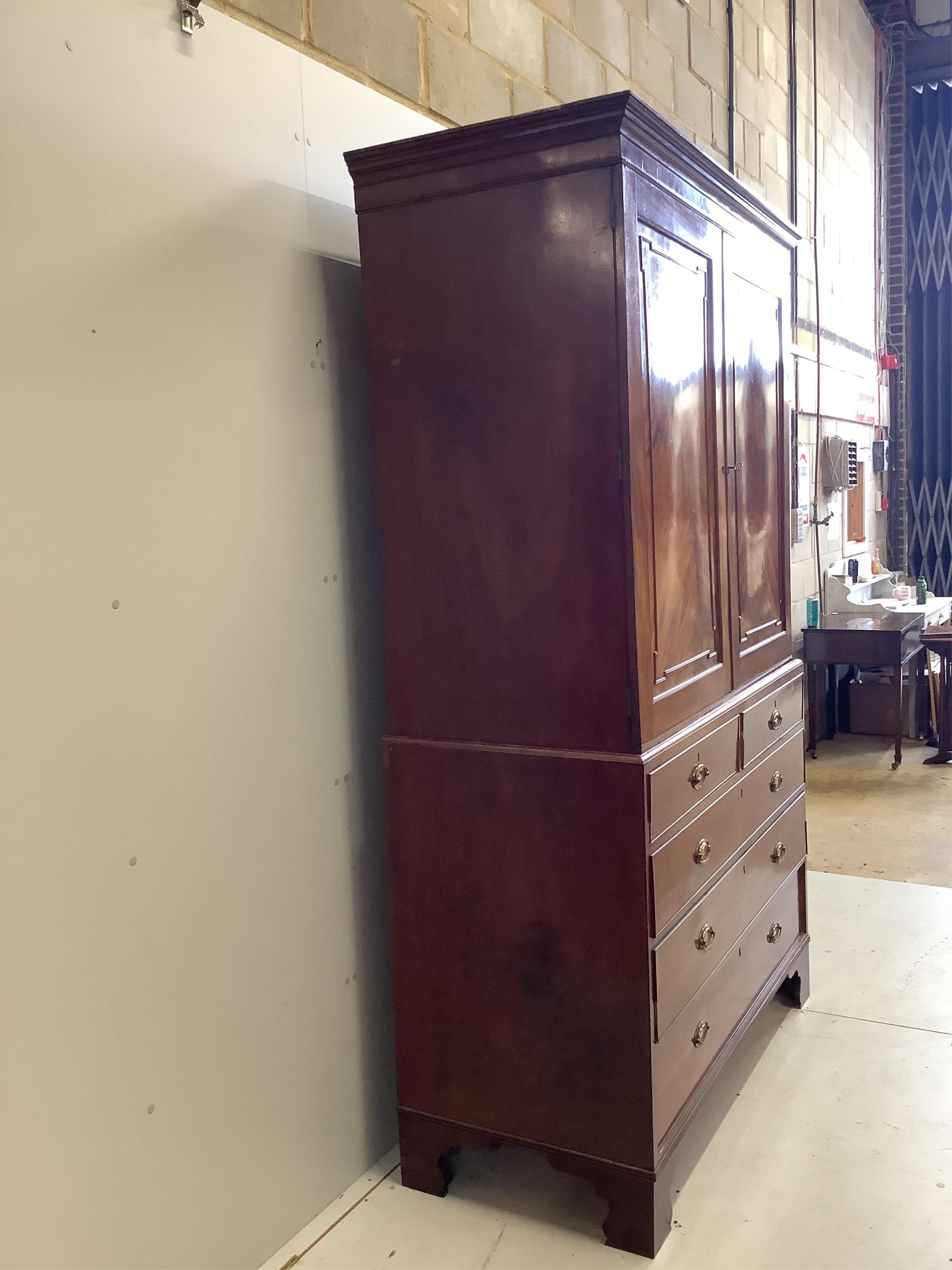 A George III mahogany linen press, converted to hanging cupboard, width 130cm, depth 58cm, height 215cm. Condition - fair, sliding trays deficient